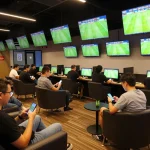 Tỷ lệ bóng đá displayed on screens as enthusiastic bettors engage with live matches in a modern sports betting lounge